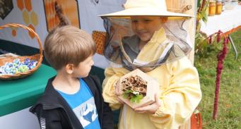 dziecko prezentuje strój pszczelarza i domek dla owadów