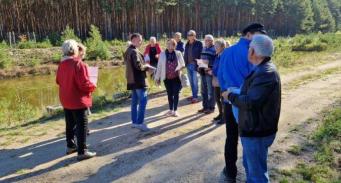 uczestnicy wyjazdu na tle zbiornika i lasu w Nadleśnictwie